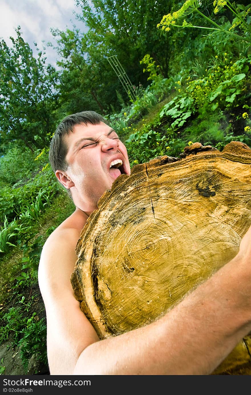 Photo of the young man, which raises huge log on the nature