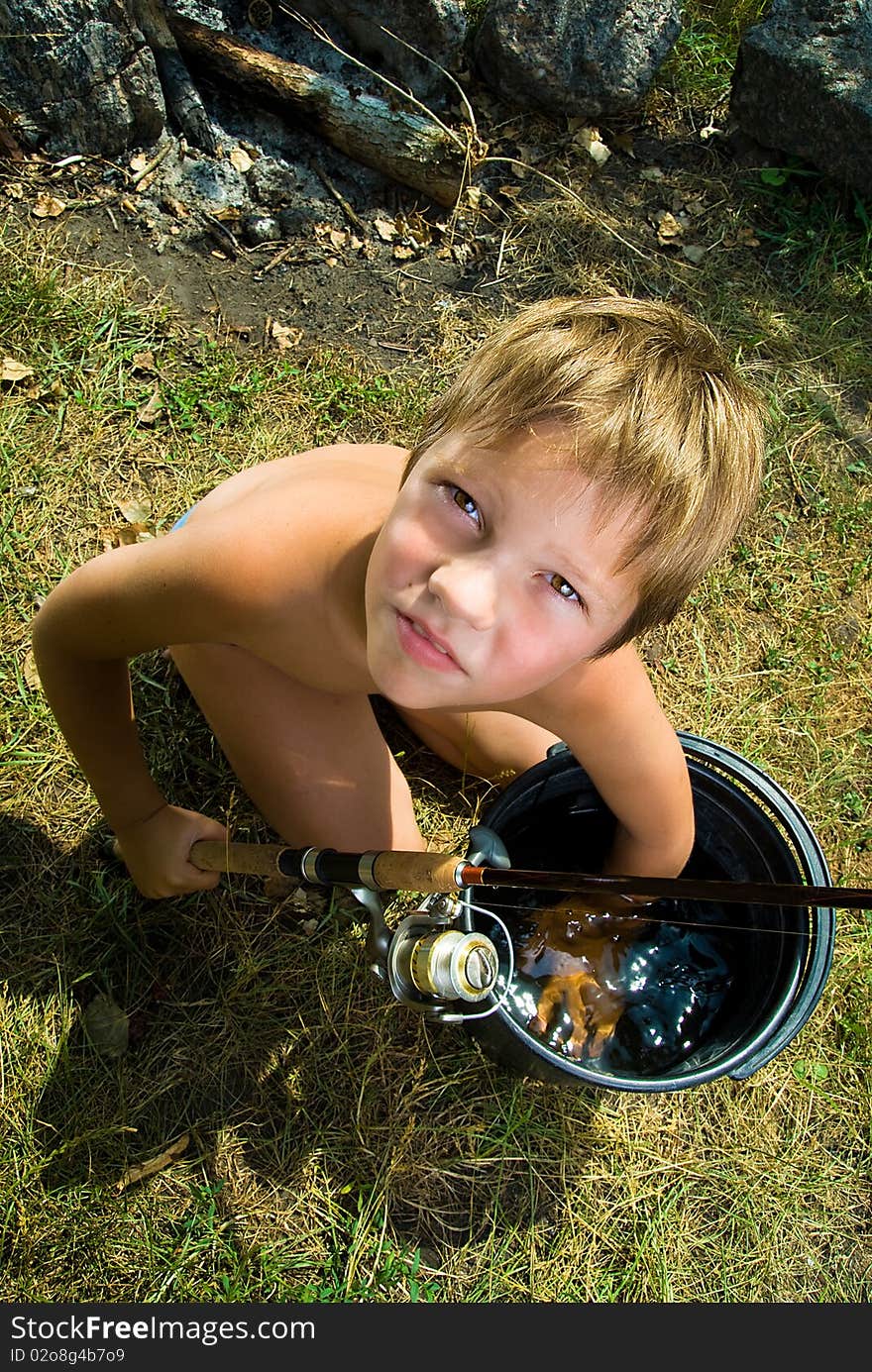 Photos of the boy with a bucket and a fishing rod, looking up, outdoors