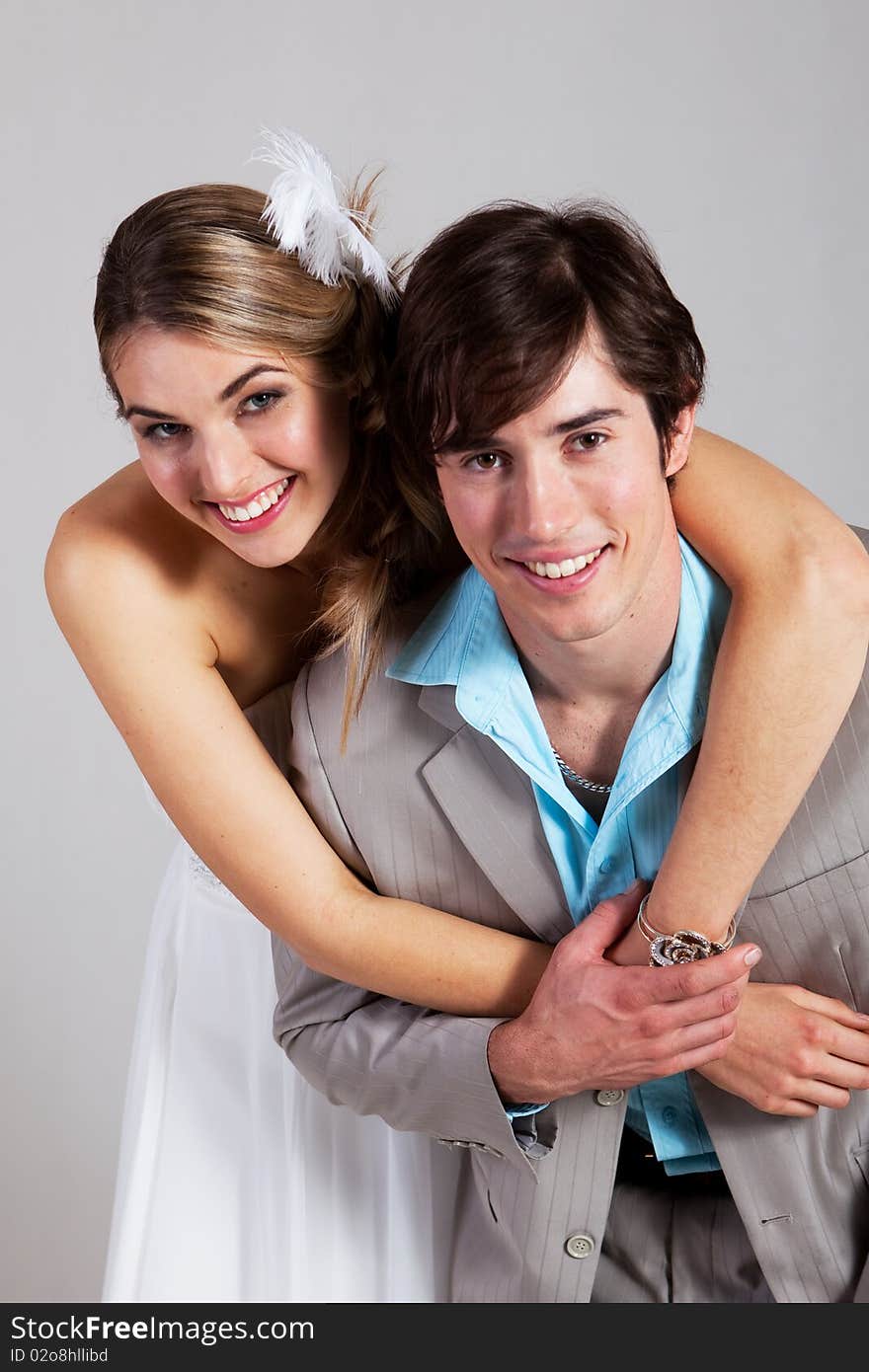 Young woman in a strapless dress has her arms around her boyfriend as the smile at the camera. Vertical shot. Young woman in a strapless dress has her arms around her boyfriend as the smile at the camera. Vertical shot.