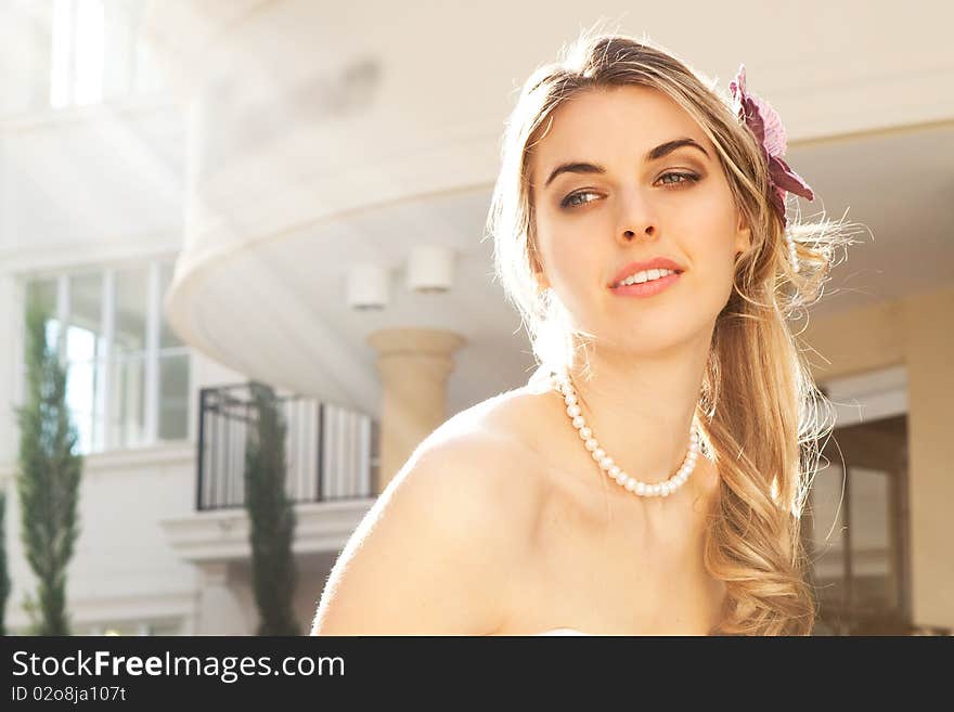 An attractive young woman wearing pearls smiles with sunlight beaming down on her. Horizontal shot. An attractive young woman wearing pearls smiles with sunlight beaming down on her. Horizontal shot.