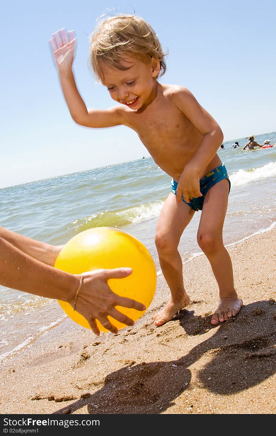 Infant kid plays ball at the sea. Infant kid plays ball at the sea