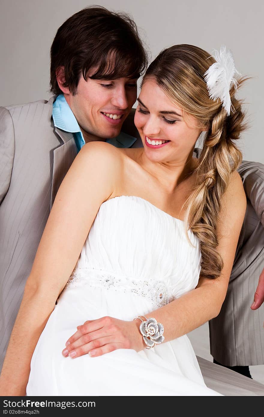 Attractive young couple sitting affectionately together. The man is wearing a suit and the woman is in a strapless dress. Vertical shot. Attractive young couple sitting affectionately together. The man is wearing a suit and the woman is in a strapless dress. Vertical shot.