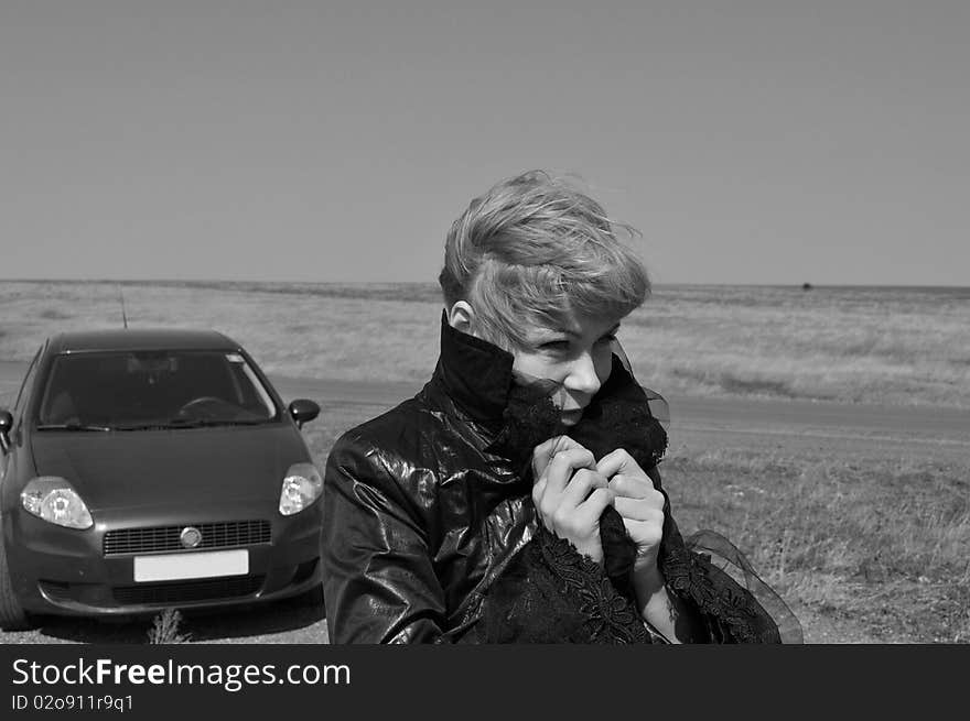 A woman raises his collar to keep warm, afraid ill, horizontal image, caption, freezing the driver who ran out of petrol on the road, gray tones. A woman raises his collar to keep warm, afraid ill, horizontal image, caption, freezing the driver who ran out of petrol on the road, gray tones.