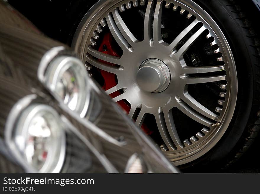 Exotic car headlight with chrome wheel in the background