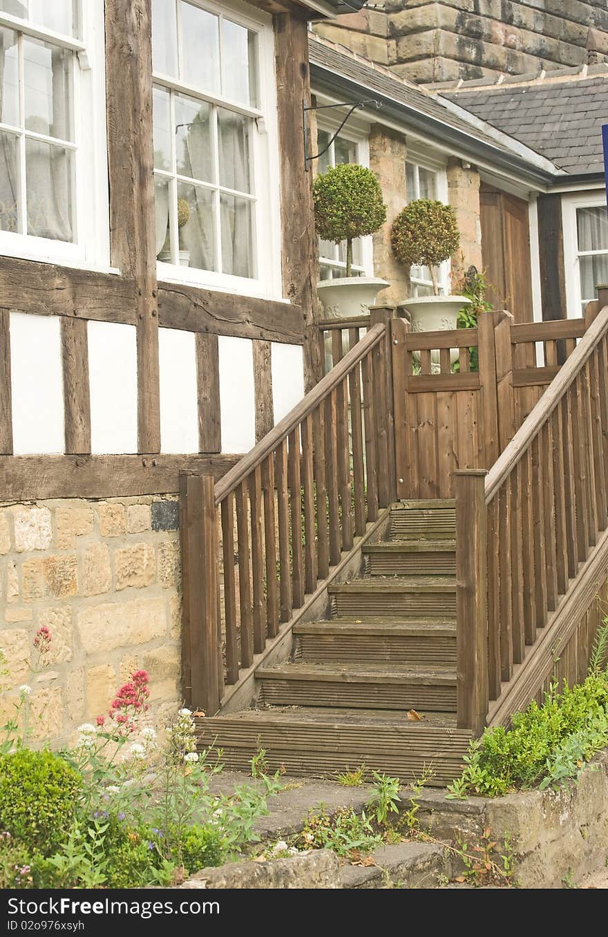 An image of an old cottage with walls of wood and lath and with a wooden stair to the garden gate. An image of an old cottage with walls of wood and lath and with a wooden stair to the garden gate.