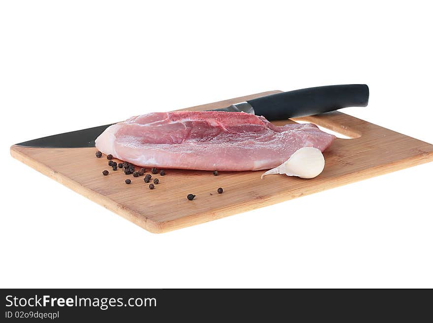 Piece of crude meat with black pepper and garlic on a kitchen board. Piece of crude meat with black pepper and garlic on a kitchen board.