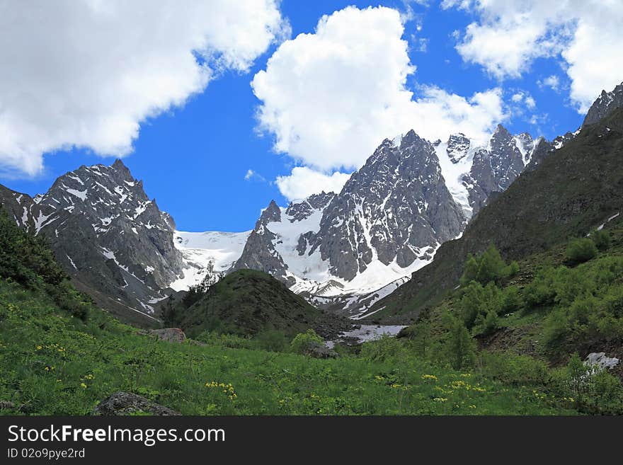 Summer sunny day in a mountain valley. Caucasus. The mountain in the centre is called  peak of aviation. Summer sunny day in a mountain valley. Caucasus. The mountain in the centre is called  peak of aviation