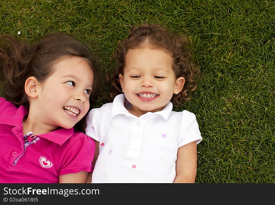 Cute little sisters laying in grass