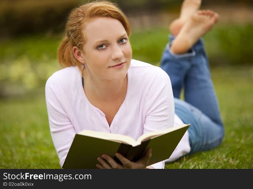 Young woman sitting outside reading. Young woman sitting outside reading