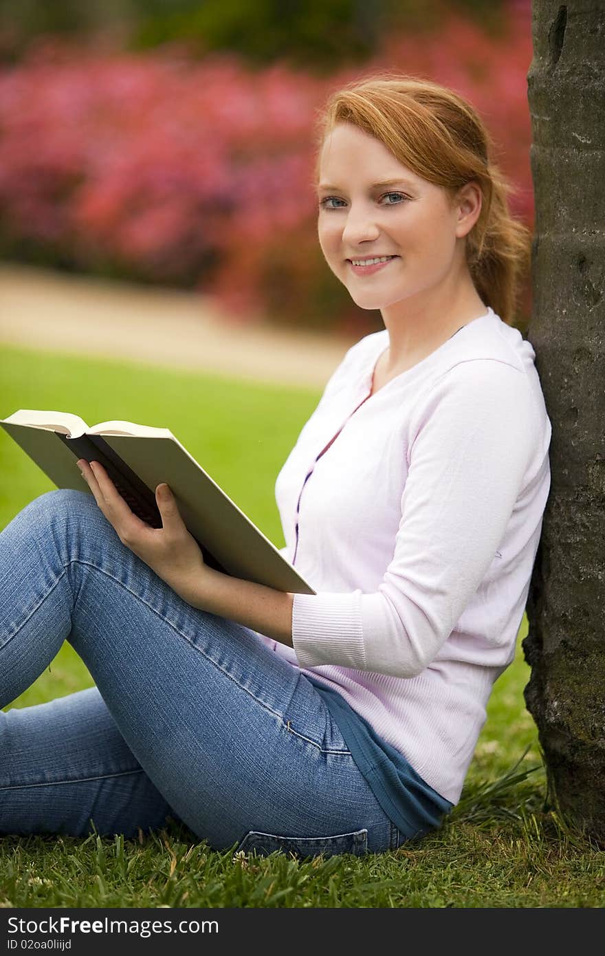 Young woman sitting outside reading. Young woman sitting outside reading