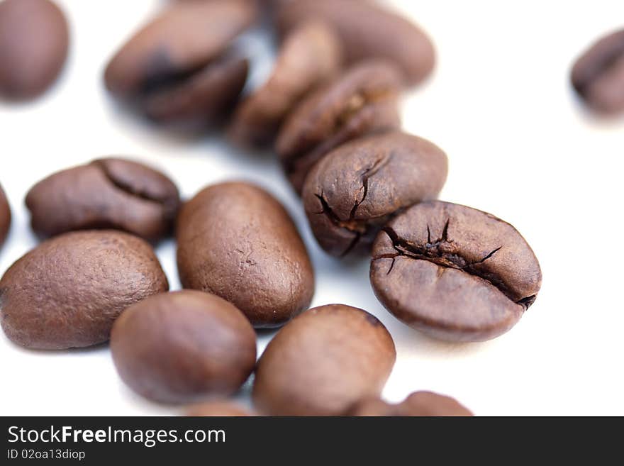 Closeup of brown roasted coffee beans isolated over white