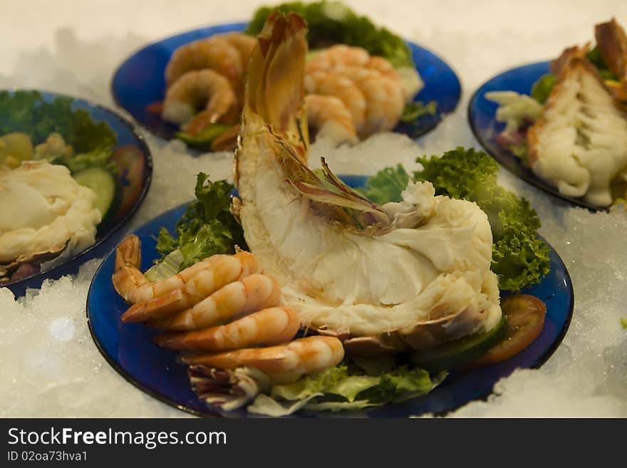 Lot of fresh delicious shrimps with decorated green salad in a fish restaurant. Lot of fresh delicious shrimps with decorated green salad in a fish restaurant.