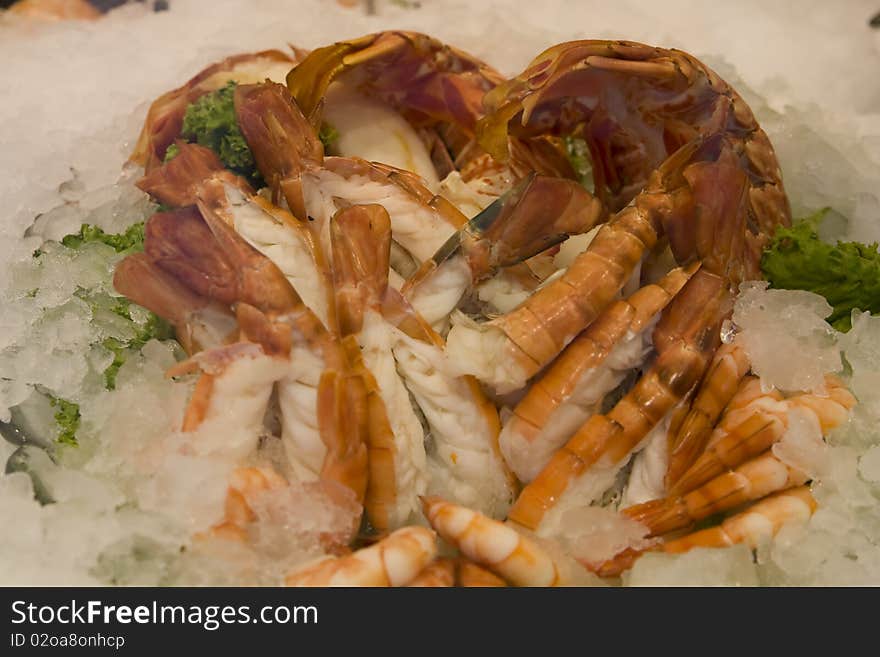 Lot of fresh delicious shrimps with decorated green salad in a fish restaurant. Lot of fresh delicious shrimps with decorated green salad in a fish restaurant.