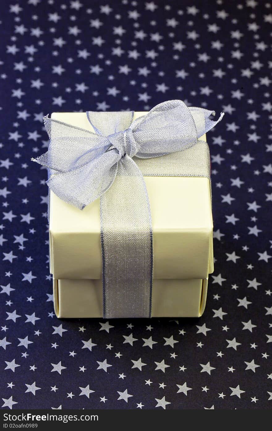 Gift box wrapped with silver ribbon on a silver stars and black background. Gift box wrapped with silver ribbon on a silver stars and black background