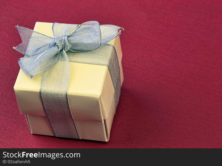 Gift box with silver ribbon over red background. Gift box with silver ribbon over red background