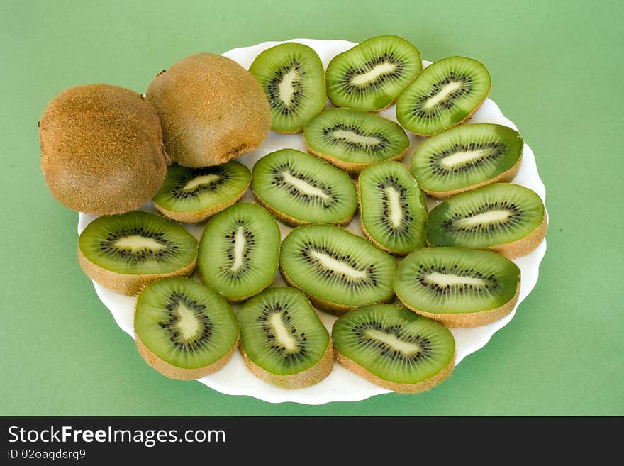 Slices of ripe fresh  kiwi on plate over green