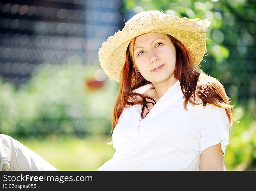 Young woman in straw hat  sitting on green grass