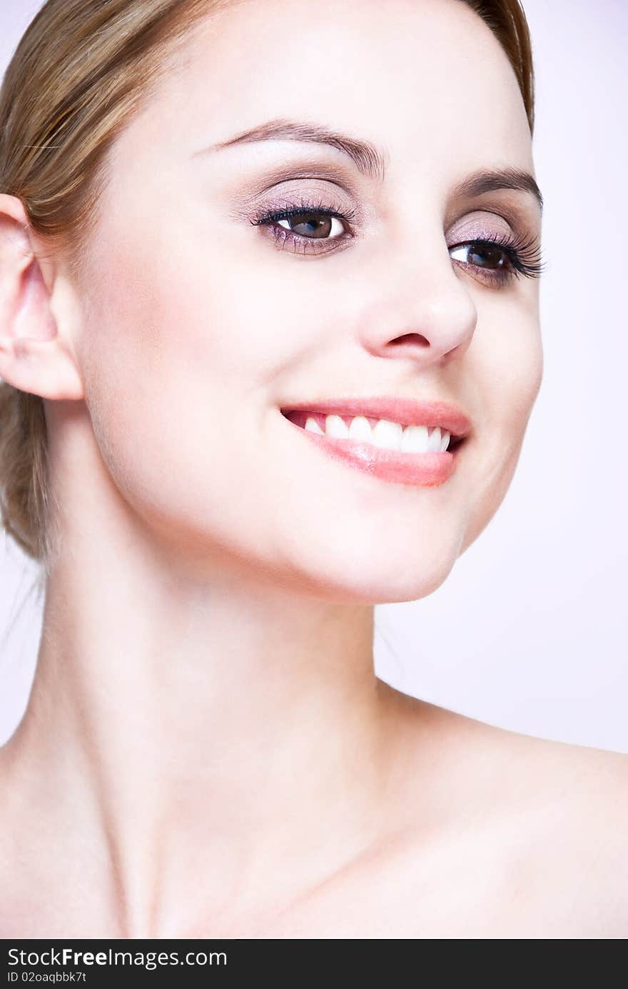 Closeup, studio shot of a young beautiful, blonde woman with smile and hair pull back. Closeup, studio shot of a young beautiful, blonde woman with smile and hair pull back