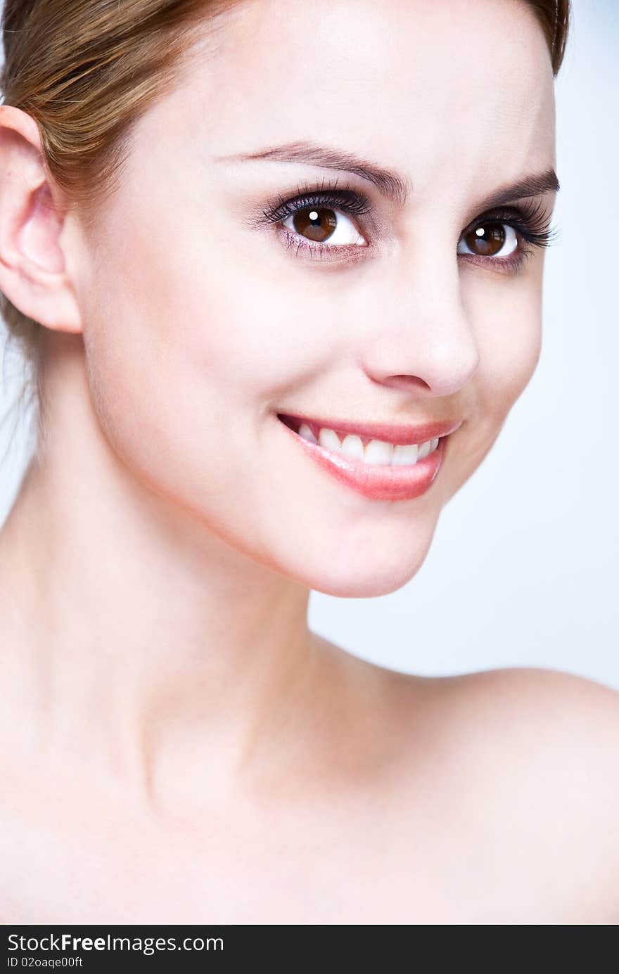 Closeup, studio shot of a young beautiful, blonde woman with smile and hair pull back. Closeup, studio shot of a young beautiful, blonde woman with smile and hair pull back