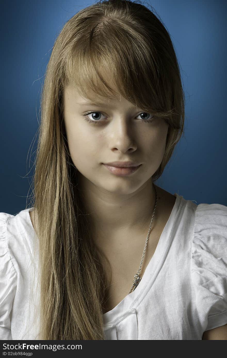 Portrait of the girl-teenager with a long blond hair on a dark blue background