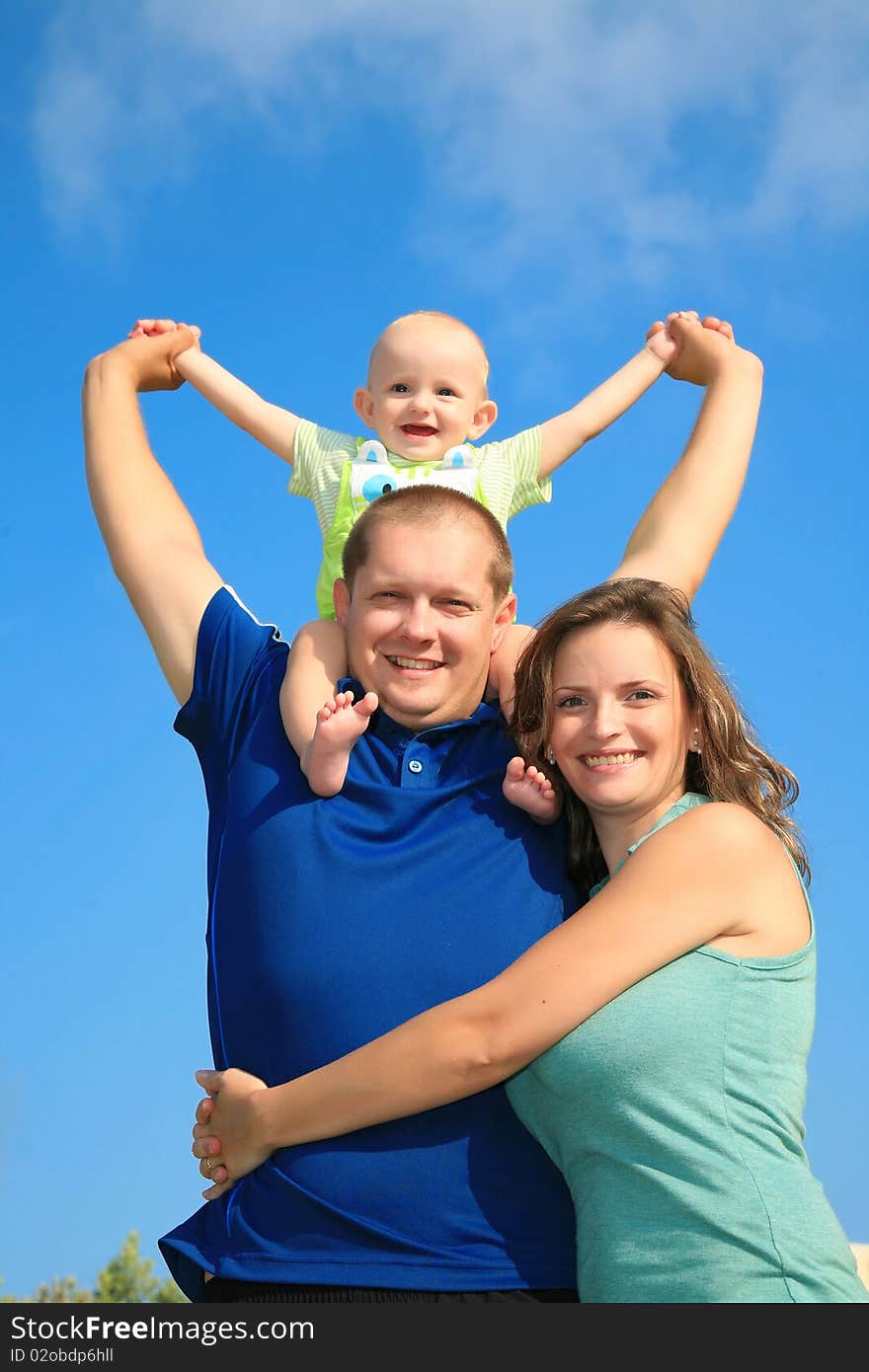 Mom dad and son happily smiling in the bright blue summer sky background. Mom dad and son happily smiling in the bright blue summer sky background