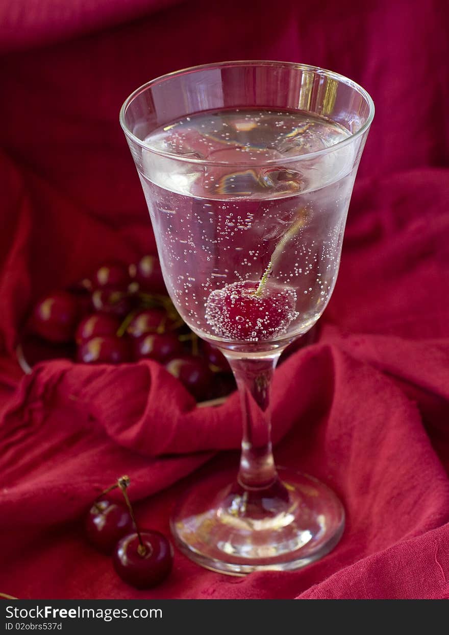 Glass of water with juicy cherry and ice