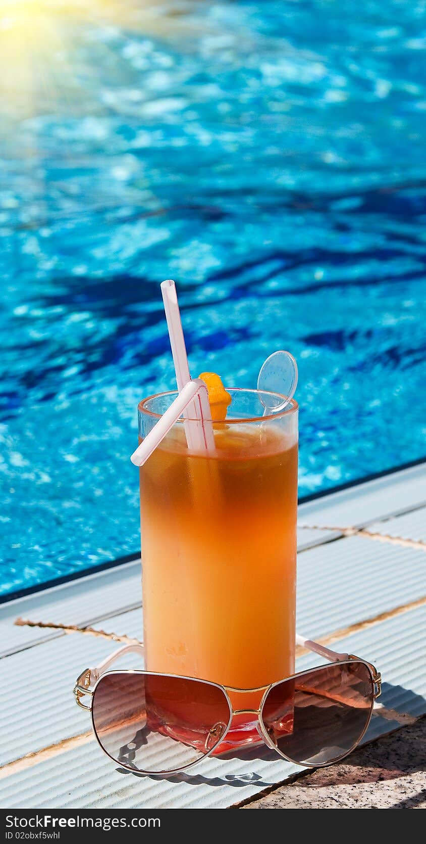 Sunglasses and tasty cocktail with lemon next to swimming pool. Sunglasses and tasty cocktail with lemon next to swimming pool.