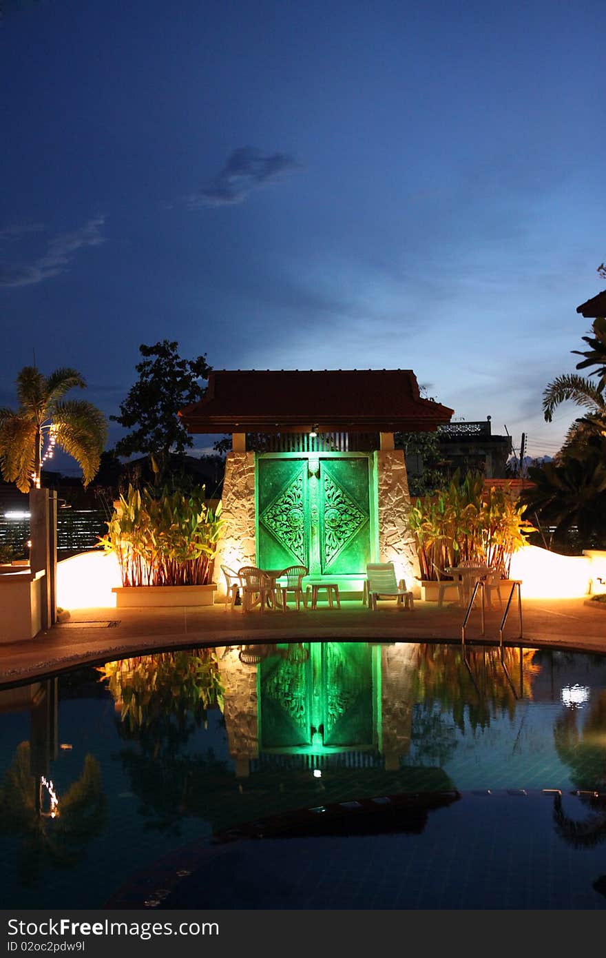 Relax corner in resort at udon thani in Thailand at night time, swimming pool and beautiful light. Background is big door which has thai art on the door.