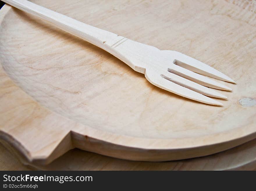 Detail of a wood fork arranged on a wood plate. Detail of a wood fork arranged on a wood plate