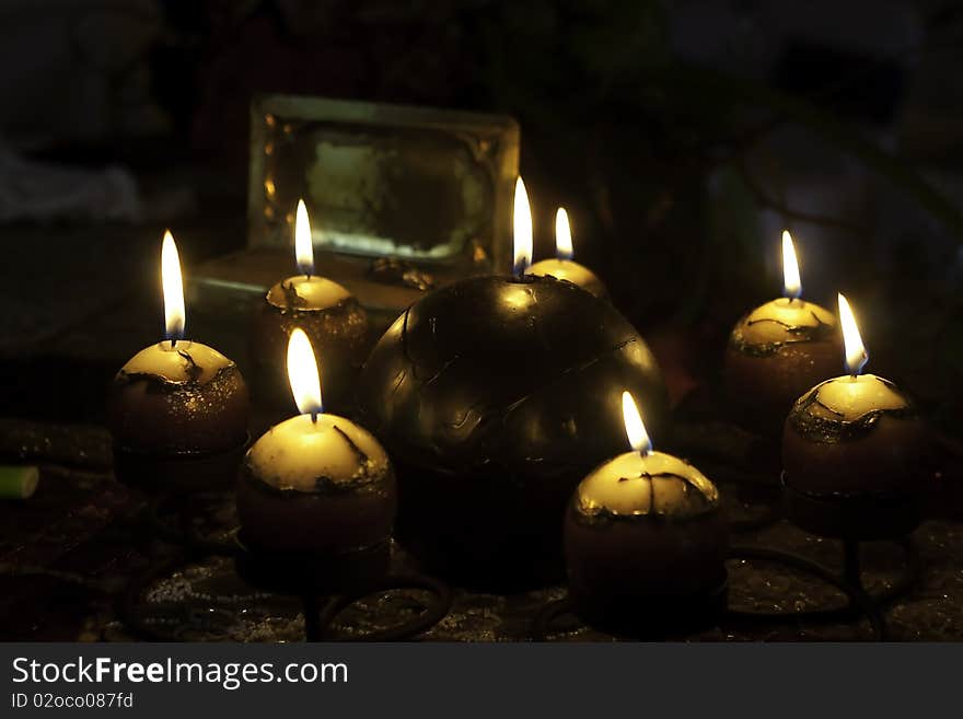 A collection of candles arranges around a bigger candle burning with soft light