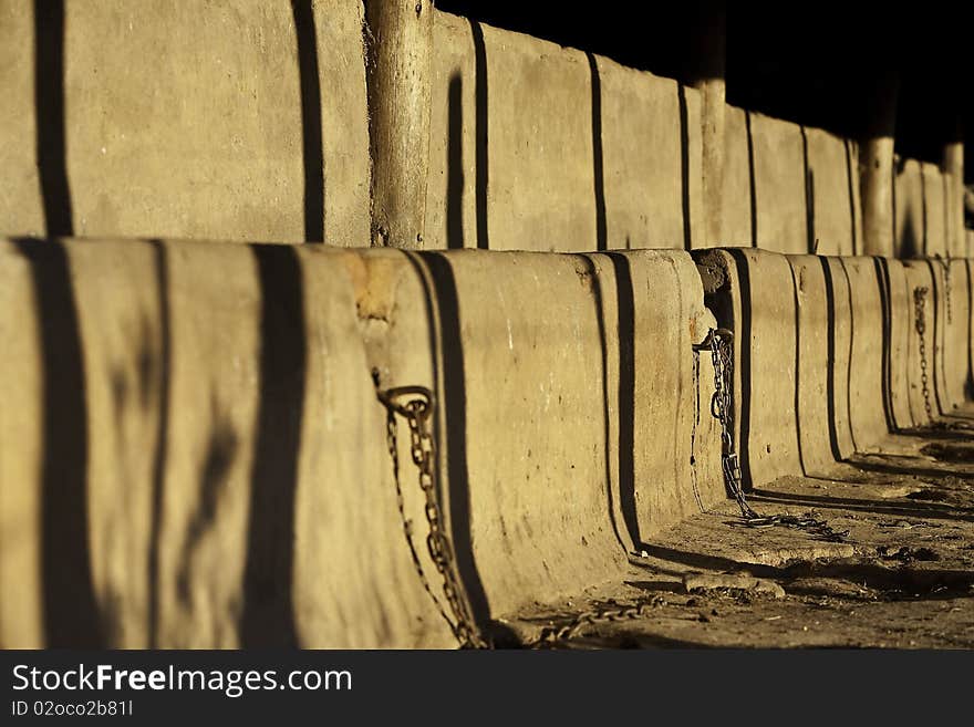 An old style  cattle stable feed trough with chains for milking in the late afternoon warm sunlight