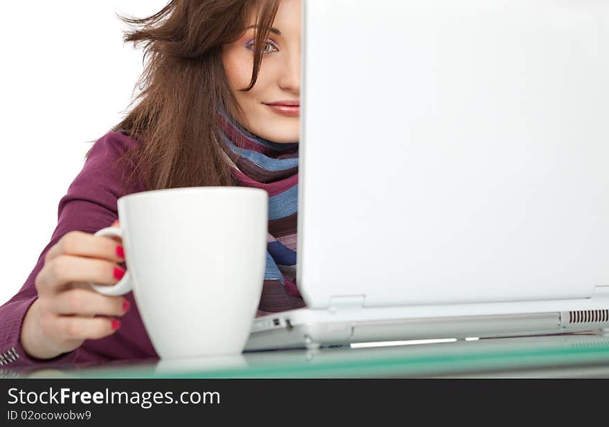 Young beautiful female sitting behind a laptop, holding a white cup. Young beautiful female sitting behind a laptop, holding a white cup