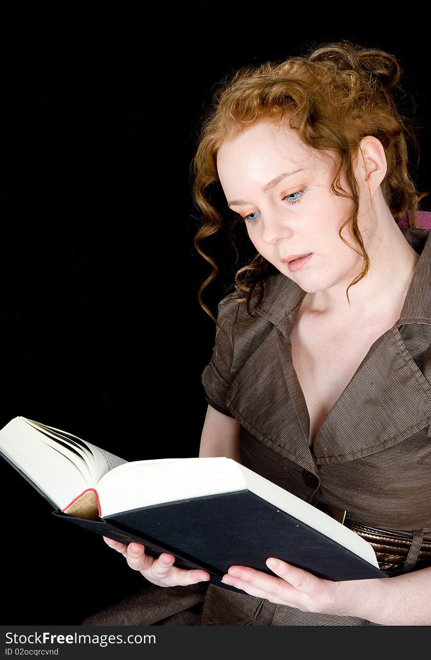 Beautiful girl with red hair reading a book