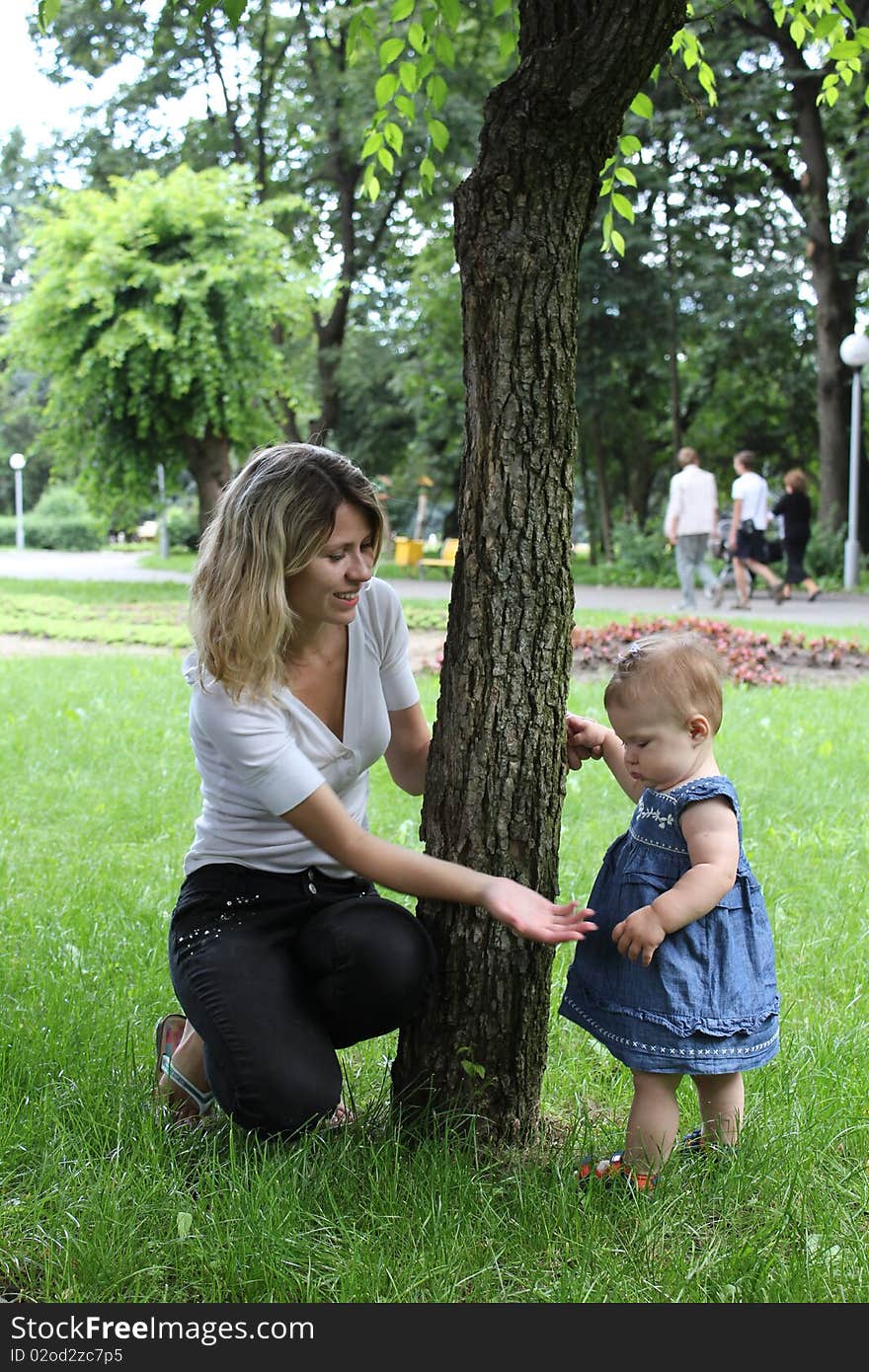 The mum with the daughter cost(stand) near a tree. The mum with the daughter cost(stand) near a tree