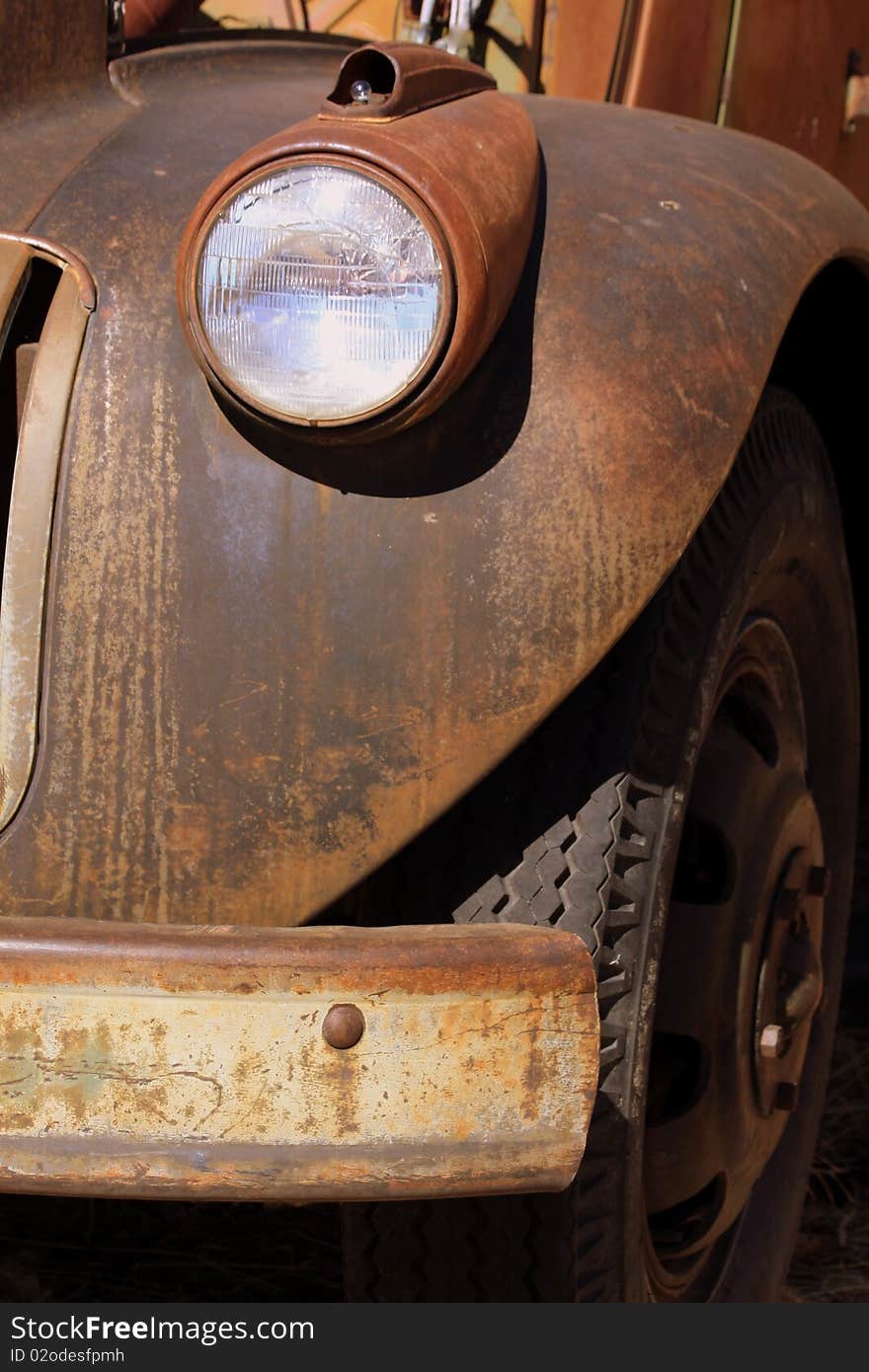 Old rusty quarter panel, bumper, and light of an antique truck sitting in a parking lot. Old rusty quarter panel, bumper, and light of an antique truck sitting in a parking lot.