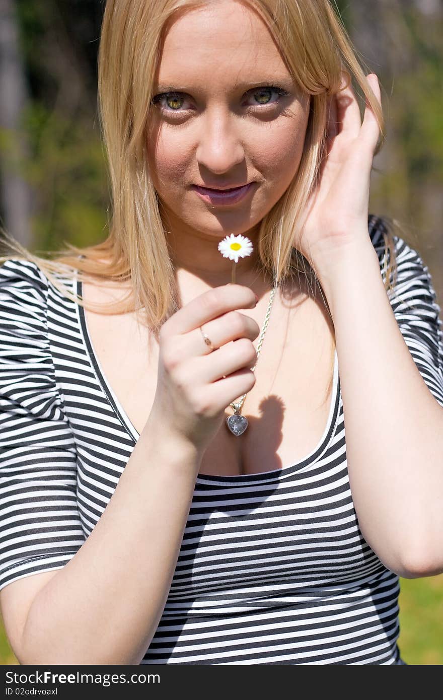 Blond girl holding and smelling Daisy flower