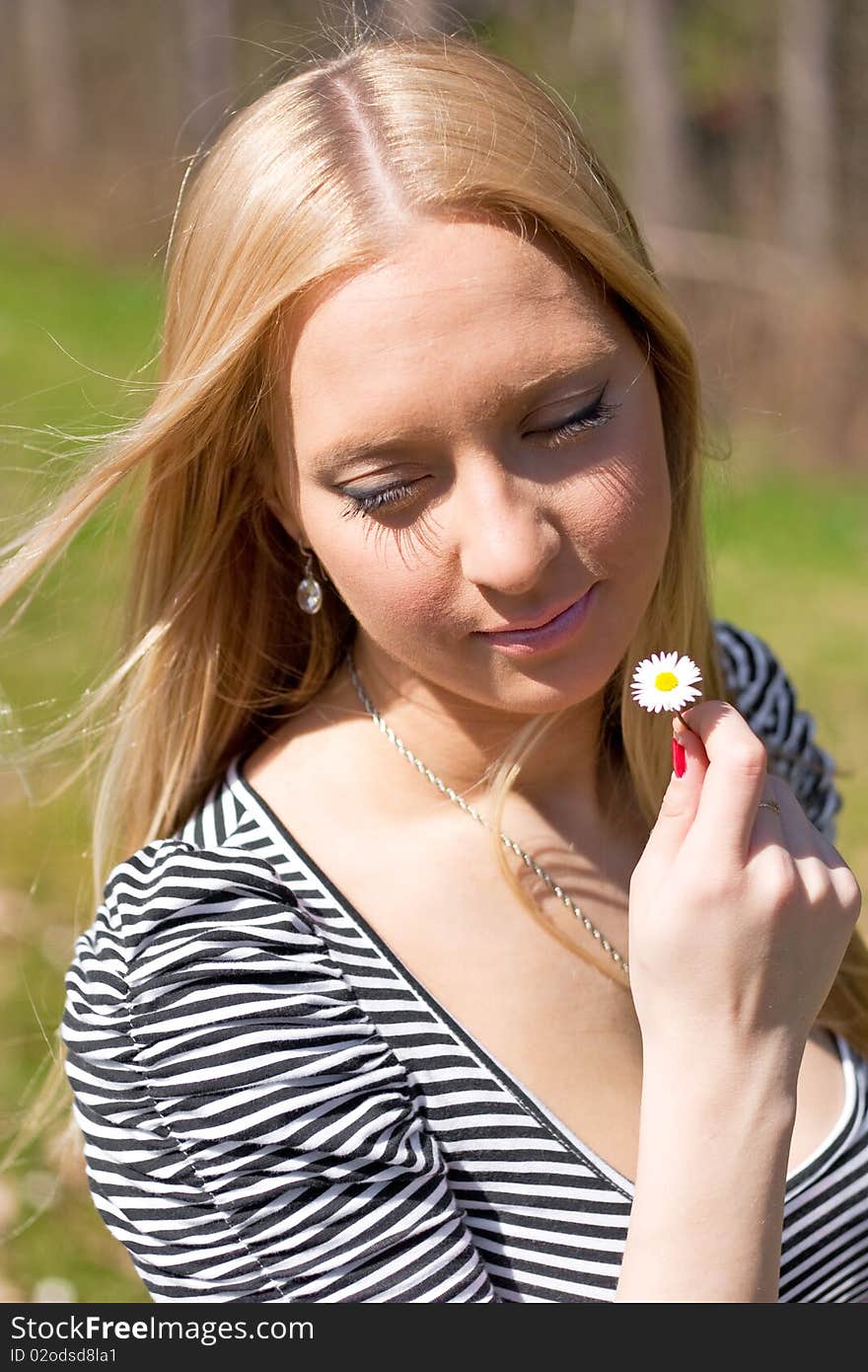 Blond girl holding and smelling Daisy flower