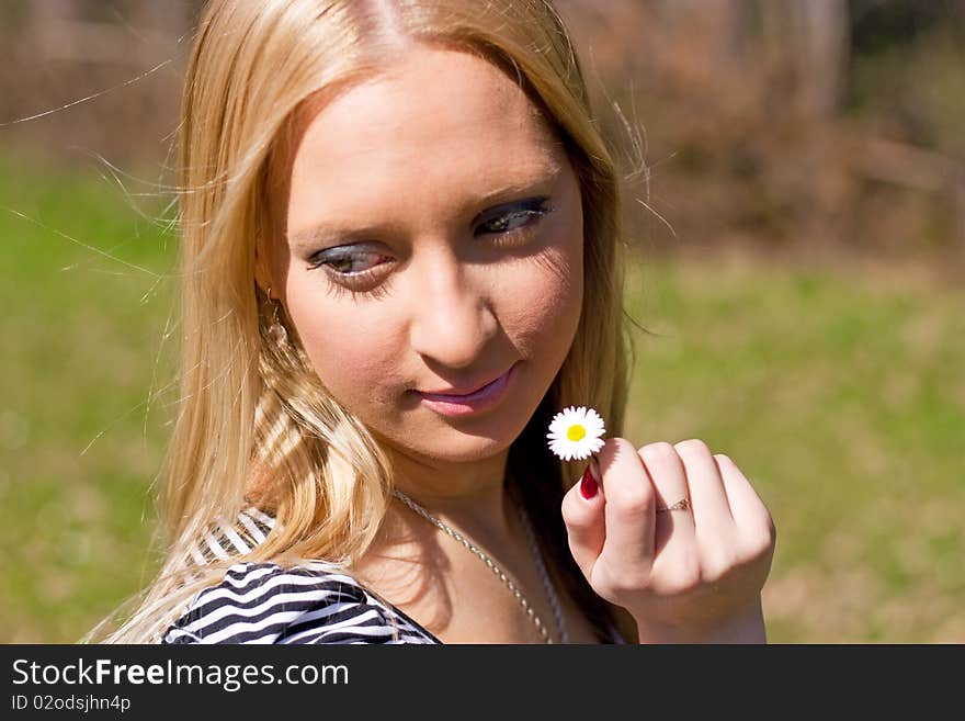 Blond girl holding and smelling Daisy flower