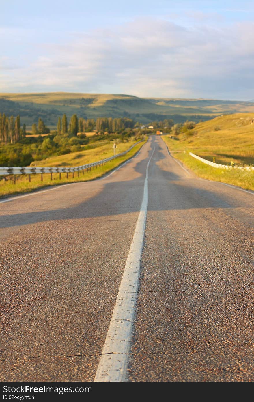 Old road led to mountains at summer daybreak.