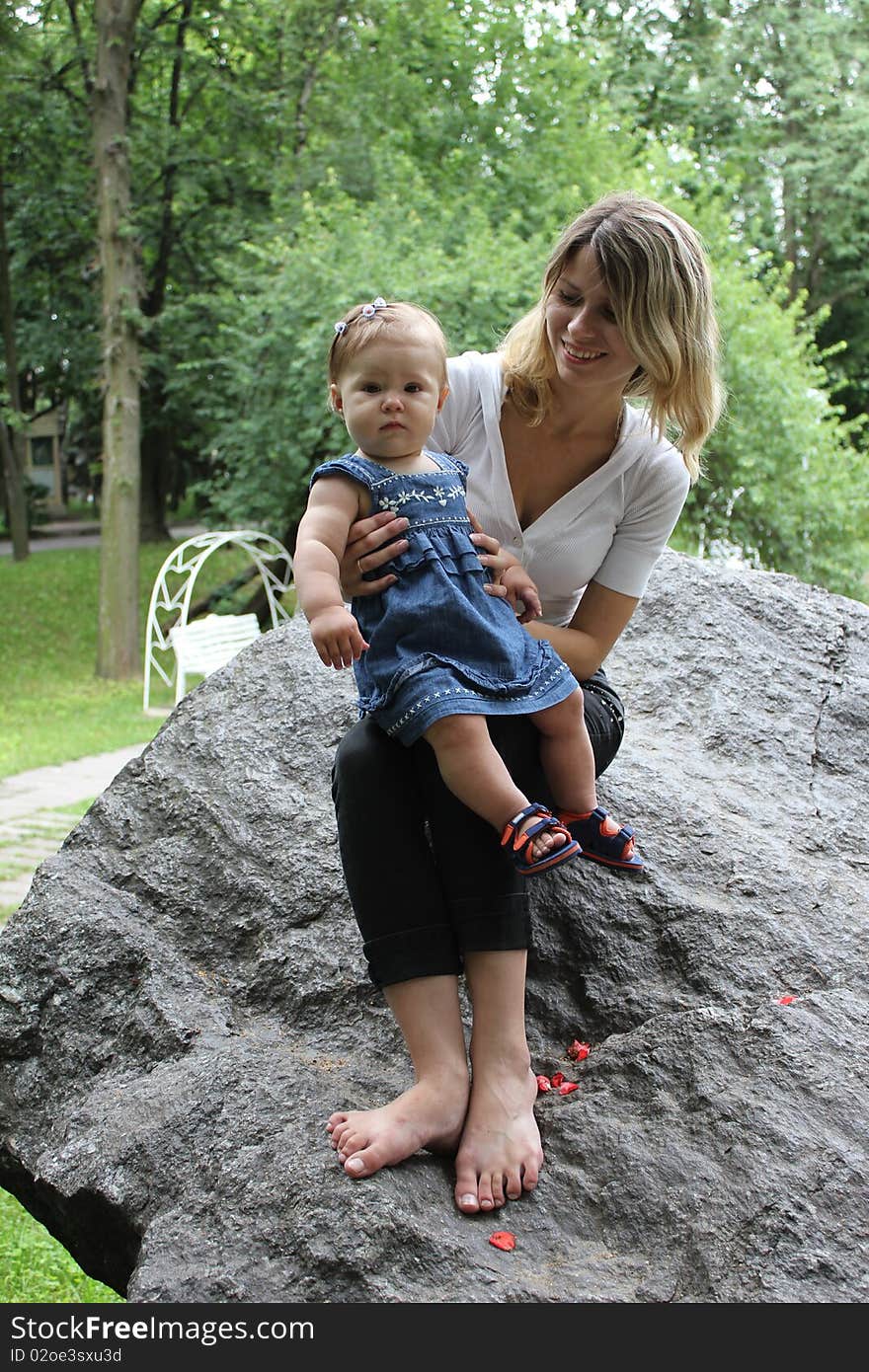 The mum with the daughter sit on a stone