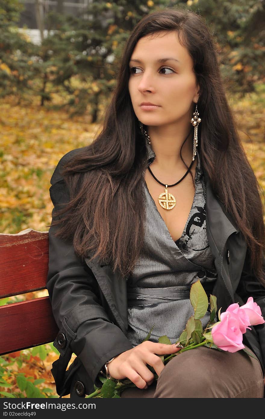 Sexual young girl with roses sits at the autumn city park