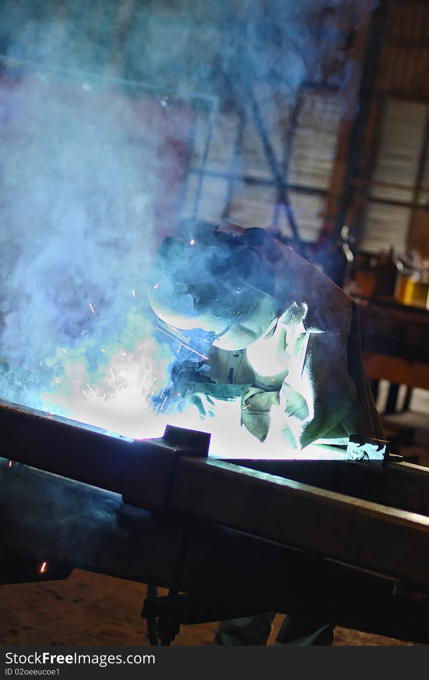 Welder wearing protective coat and mask welding something. Welder wearing protective coat and mask welding something