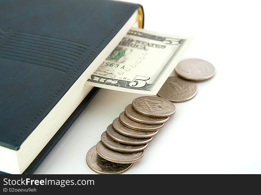 Dollar invested in the diary as a bookmark with a stack of coins lying beside it