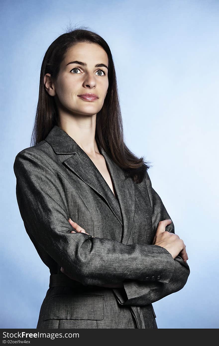 Half-body portrait of smiling confident businesswoman with entwined arms in grey suit looking up-right. Half-body portrait of smiling confident businesswoman with entwined arms in grey suit looking up-right.