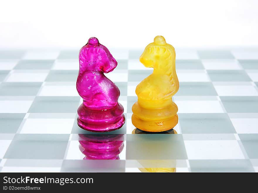 Two Knight chess pieces from opposite sides face off. Two Knight chess pieces from opposite sides face off.