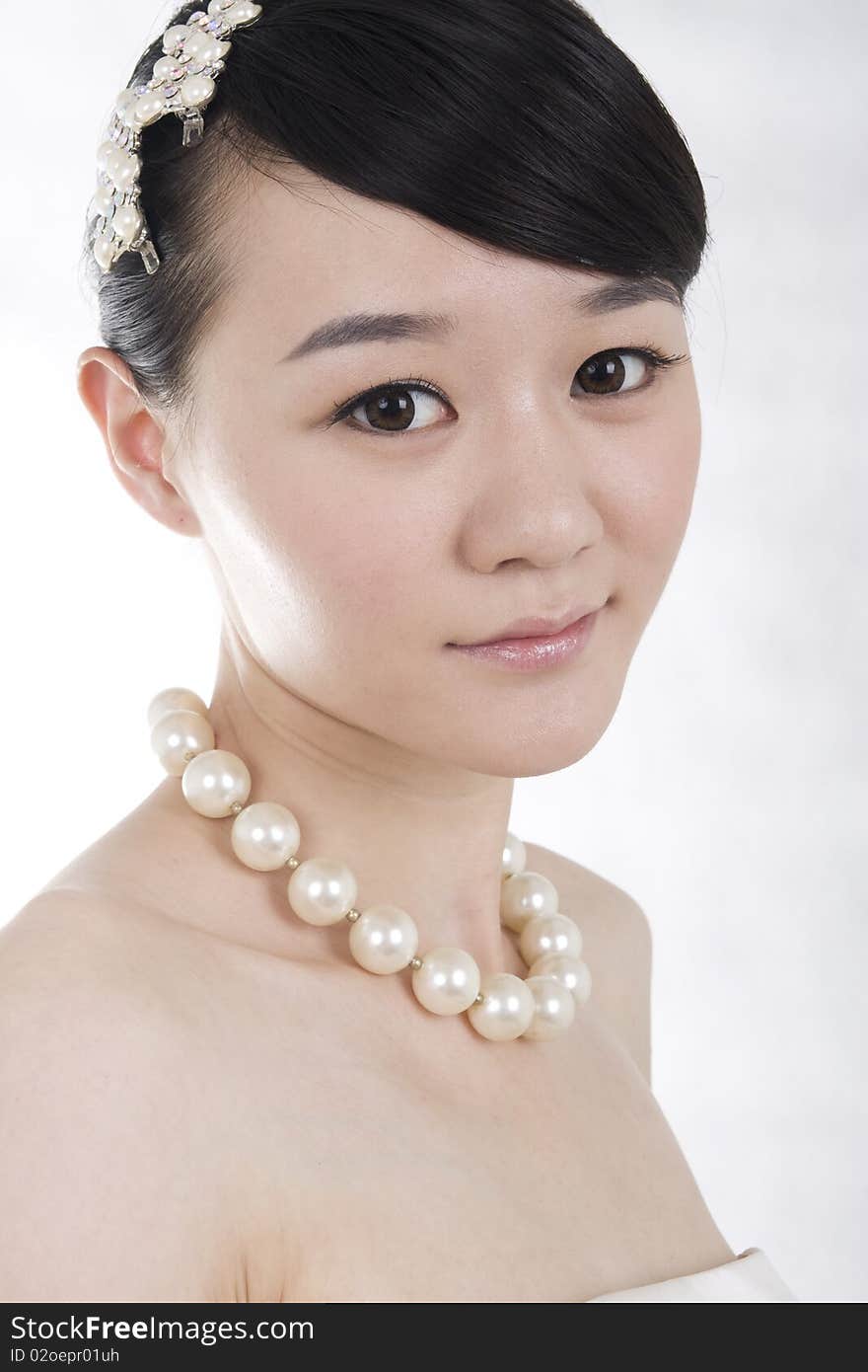 Beautiful bride with perfect natural makeup,smiling,headgear on head,wearing pearl necklace