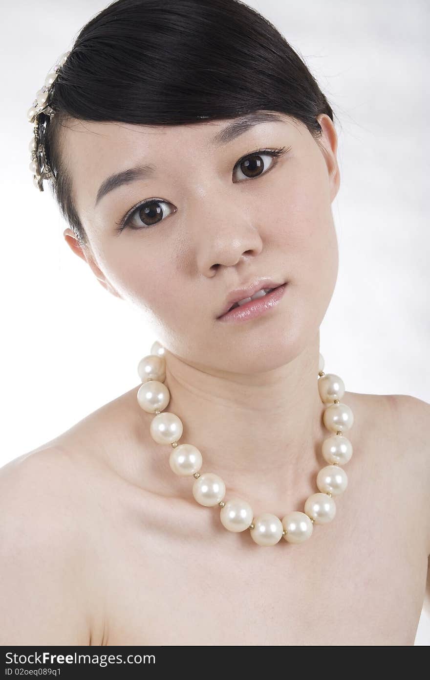 Beautiful bride with perfect natural makeup,headgear on head,wearing pearl necklace