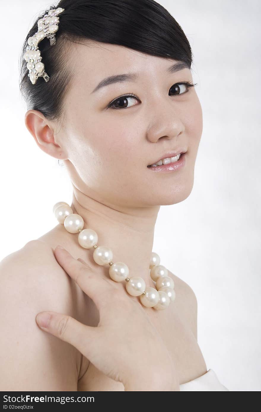 Beautiful bride with perfect natural makeup,smiling,headgear on head,wearing pearl necklace