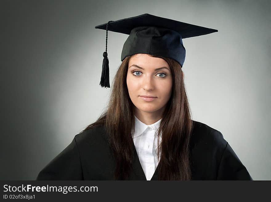 Young beauty graduate woman on gray background