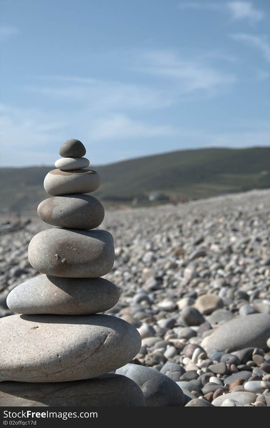 Stone tower on seaside with hilly background and blue sky